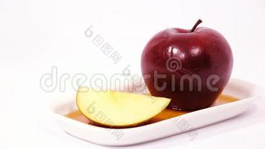 将蜂蜜倒入红苹果上，将红苹果切片在白色背景上分离蜂蜜