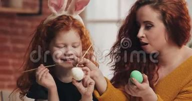 复活节快乐。 妈妈和她的小女儿画鸡蛋。 为复活节<strong>做准备</strong>的幸福家庭。 他们戴着兔子耳朵