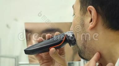 年轻人在浴室用电动剃须刀刮胡子