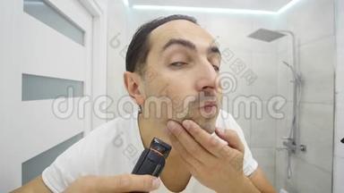 年轻人在浴室用电动剃须刀刮胡子