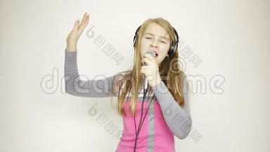 年轻女孩听着耳机里的音乐，<strong>拿</strong>着麦克风，<strong>唱歌</strong>和有趣的舞蹈