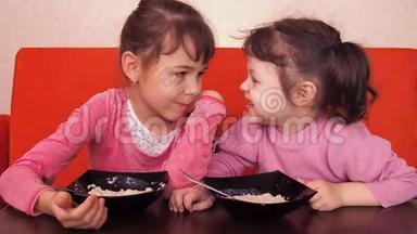 孩子们<strong>吃</strong>粥。 两个小女孩<strong>吃</strong>粥。 两个姐妹坐在橙色的沙发上<strong>吃</strong>晚饭。