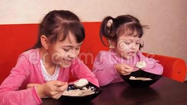 孩子们<strong>吃</strong>粥。 两个小女孩<strong>吃</strong>粥。 两个姐妹坐在橙色的沙发上<strong>吃</strong>晚饭。