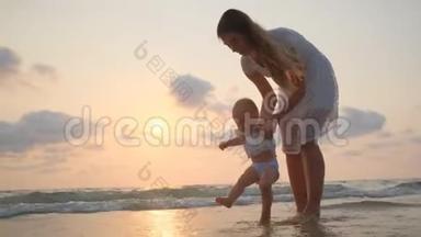 夕阳西下，年轻美丽的女人带着她的小宝宝在海滨散步