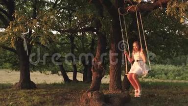 小女孩在阳光下的树下荡秋千，和孩子们一起玩。 特写镜头。 家庭的乐趣。 儿童<strong>乘车</strong>