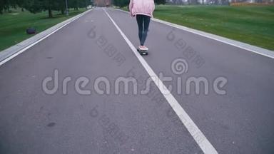 年轻漂亮的金发女郎穿着粉红色的风挡，<strong>玩滑板</strong>，滑着长板下山