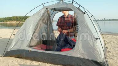 一个成熟的人在海边的户外度假时收集帐篷