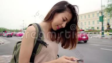 亚洲女游客背包客微笑，使用智能手机独自旅行，在曼谷的城市街道户外度假-泰国