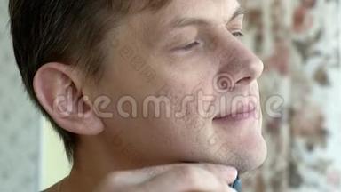 男人用电动剃须刀刮胡子。 检查剃须刀在脸颊上<strong>滑动手指</strong>。 特写镜头。