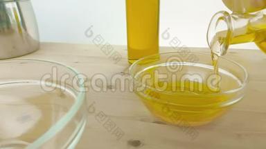 在靠近橄榄油瓶的木桌背景上的白色容器中倒入<strong>食用油</strong>，慢镜头拍摄