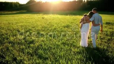 家庭幸福。 爸爸妈妈和一个小女孩，在夕阳下穿着白色衣服的田野里散步