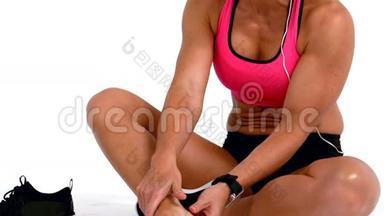 受伤的女运动员坐着触摸脚踝