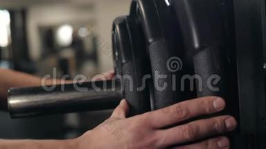 在健身房里用杠铃做运动，把杠铃牌放在手里宏观调控