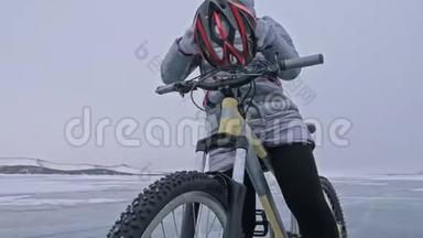 女人穿着运动装备。 女孩穿着银色<strong>羽绒服</strong>，自行车背包和头盔。 冰的冰