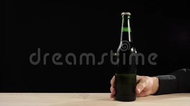 新鲜<strong>啤酒</strong>。 手把一个绿色的瓶子和<strong>美</strong>味的工艺<strong>啤酒</strong>放在一个的桌子在黑色的背景下。 冷鲜<strong>啤酒</strong>