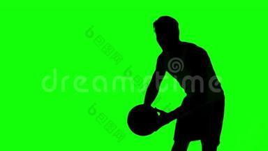 一个人在绿色屏幕上扔篮球的剪影