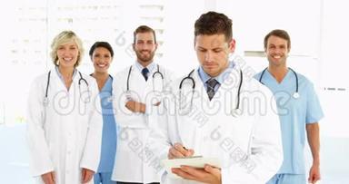 医生在剪贴板上写字，而工作人员则站在他身后