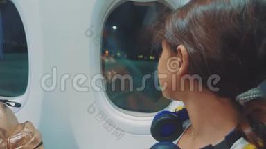 少女航空飞机概念。 年轻的女孩看着外面的生活方式，坐在窗边的飞机。 夜间飞行