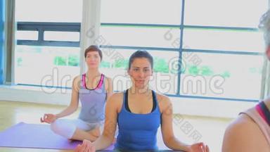 在<strong>瑜伽</strong>课上，微笑的女人坐在<strong>瑜伽垫</strong>上