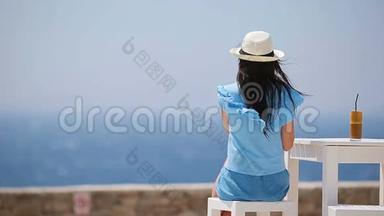 年轻女孩喝着冷咖啡<strong>享受</strong>海景。 美丽的女人在海滩上<strong>享受</strong>异国情调的假期放松