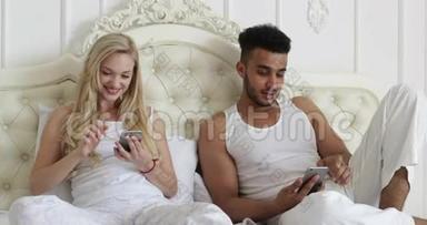 情侣卧床使用智能手机，混搭男女笑早卧室
