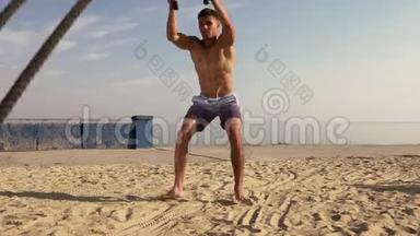 在海滩上使用战斗<strong>绳索</strong>的年轻肌肉男训练