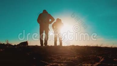 团队合作智能手机导航。 两名游客徒步旅行者在日落时带着背包去徒步旅行。 徒步旅行者冒险