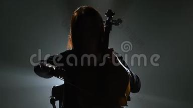 一个在<strong>黑</strong>暗工作室里有大提琴的音乐家的剪影。 <strong>黑烟</strong>背景