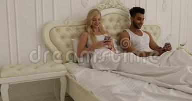 情侣卧床使用智能手机，混搭男女笑早卧室