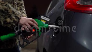 女人在冬天的加油站给她的车加油
