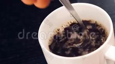 在黑木桌上<strong>用勺子</strong>拿着成人手喝咖啡的顶部