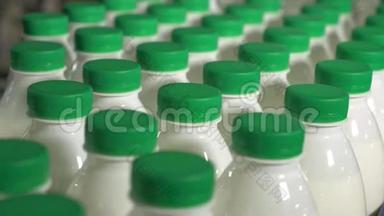 瓶子里的牛奶在传送带上移动。 牛奶厂传送带上有绿色帽子的牛奶。