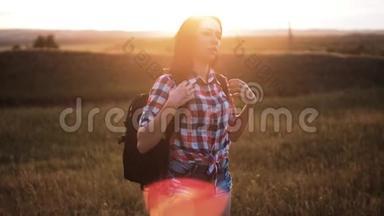 年轻姑娘背着背包走着，在峰后欣赏日落。 背景视图上的游客模型慢