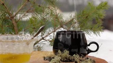 带蜂蜜的茶具：把热茶从透明的茶壶倒到雪中的黑杯子