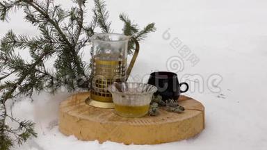 带蜂蜜的茶具：把热茶从透明的茶壶倒到雪中的黑杯子