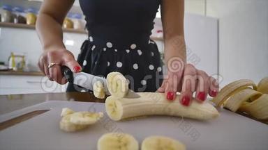 女人在家庭厨房的木制厨房板上切<strong>香</strong>蕉。 在家做饭。 厨房里的家庭气<strong>氛</strong>