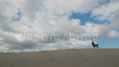 女孩站在沙丘上穿着绿色的衣服，风