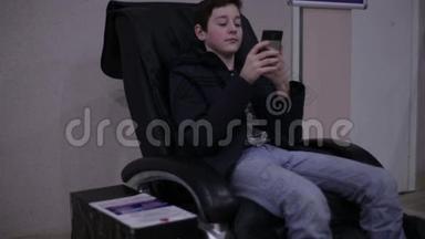青少年坐在<strong>按摩椅</strong>上，拿着智能手机