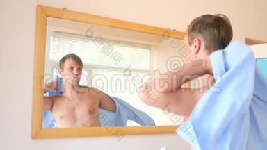 一个开朗可爱的男人在镜子前穿衣服，对着镜子微笑。 4k，慢动作
