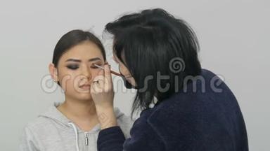 专业造型师化妆师在视觉工作室里为一个亚洲女孩化妆。