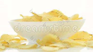 不健康的有害食物，黄色美味的土豆肋脆片随机躺在碗和白色的桌子背景上，近距离。