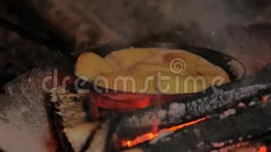 在露天篝火上用碳钢煎锅煎炸黄油土豆