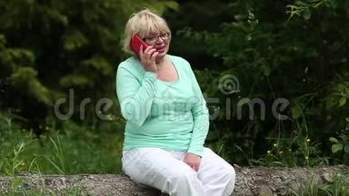 女人坐在森林中一棵倒下的树上，通过智能手机进行交流
