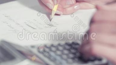 女人用铅笔写字，用计算器<strong>打字</strong>