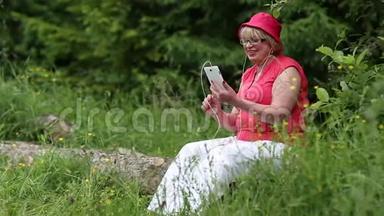 女人坐在森林中一棵倒下的树上，通过智能手机进行<strong>交流</strong>