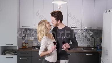 年轻夫妇在家里的厨房里喝红酒