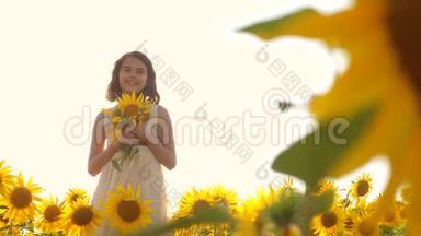夏天，快乐的小女孩在田野上闻着一朵向日葵。 慢动作视频。 站在田野里的少女