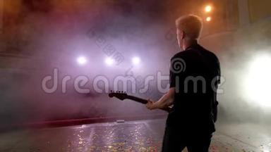 吉他手在舞台上表演。 舞台灯光，烟雾..