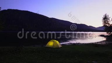 黄色帐篷在山湖畔花费.. <strong>晚安</strong>。 在帐篷里，光线燃烧。