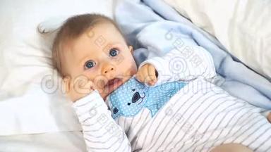 有着蓝色大眼睛和金发的婴儿在床上